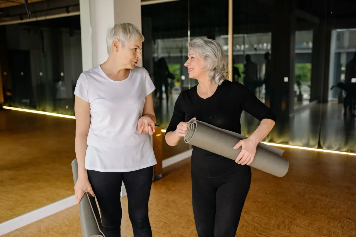 Two regular members catching up with their mats after class, the kind of loyalty a membership plan is built for