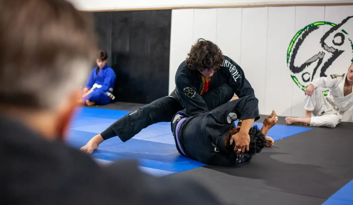 Two students grappling on the mats during a Brazilian Jiu-Jitsu class